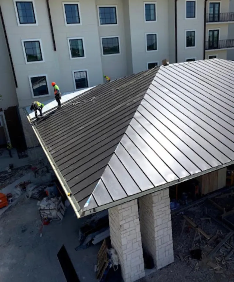 Crew installing standing seam metal roof panels on a commercial project in Harrodsburg
